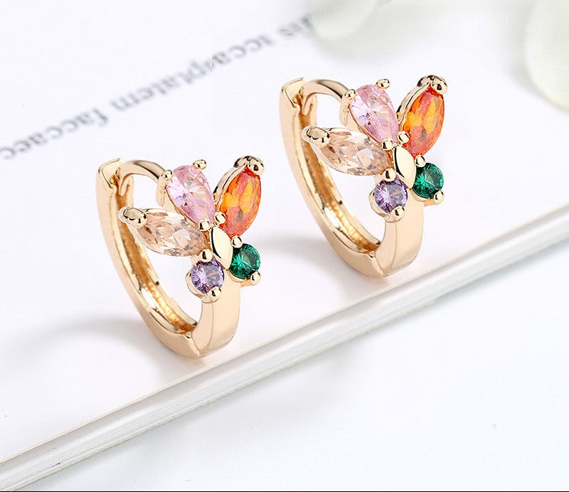 Butterfly-shaped earrings with colorful gemstones on a white surface.