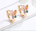 Butterfly-shaped earrings with colorful gemstones on a white surface.